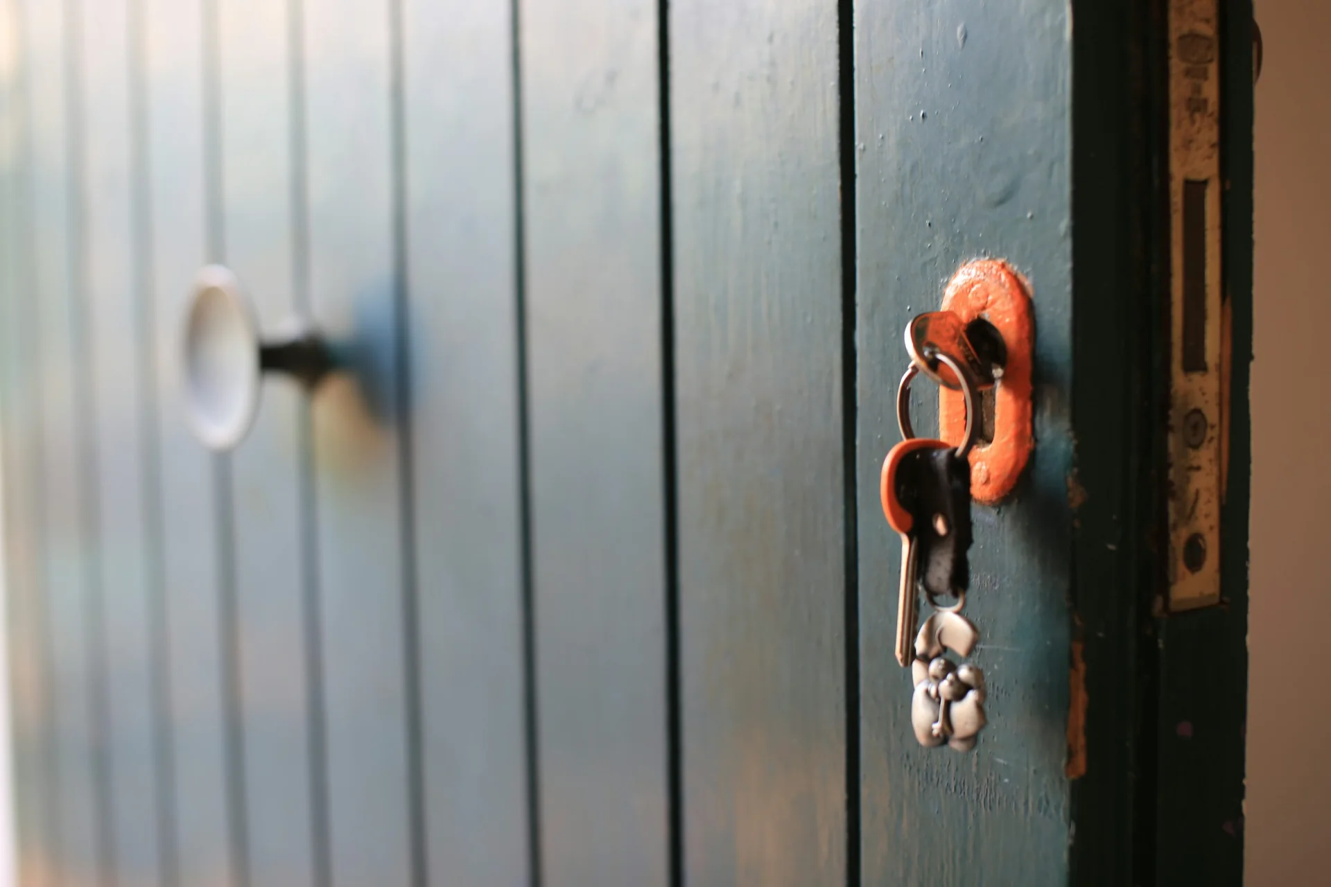 Key ring hanging from a lock in a weathered blue wooden door