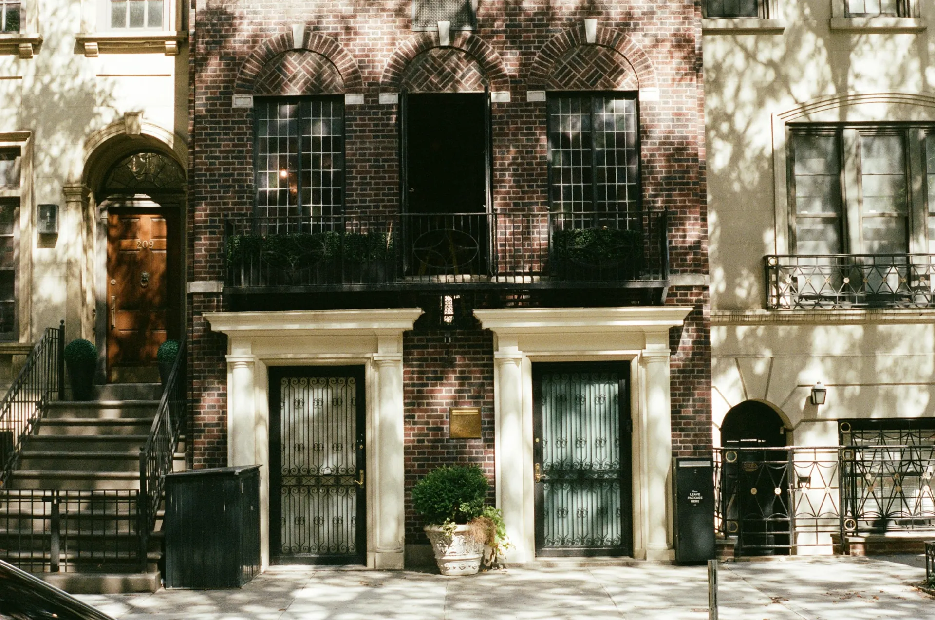 Residential entrance doors and iron railings on a brick-and-stone Manhattan street