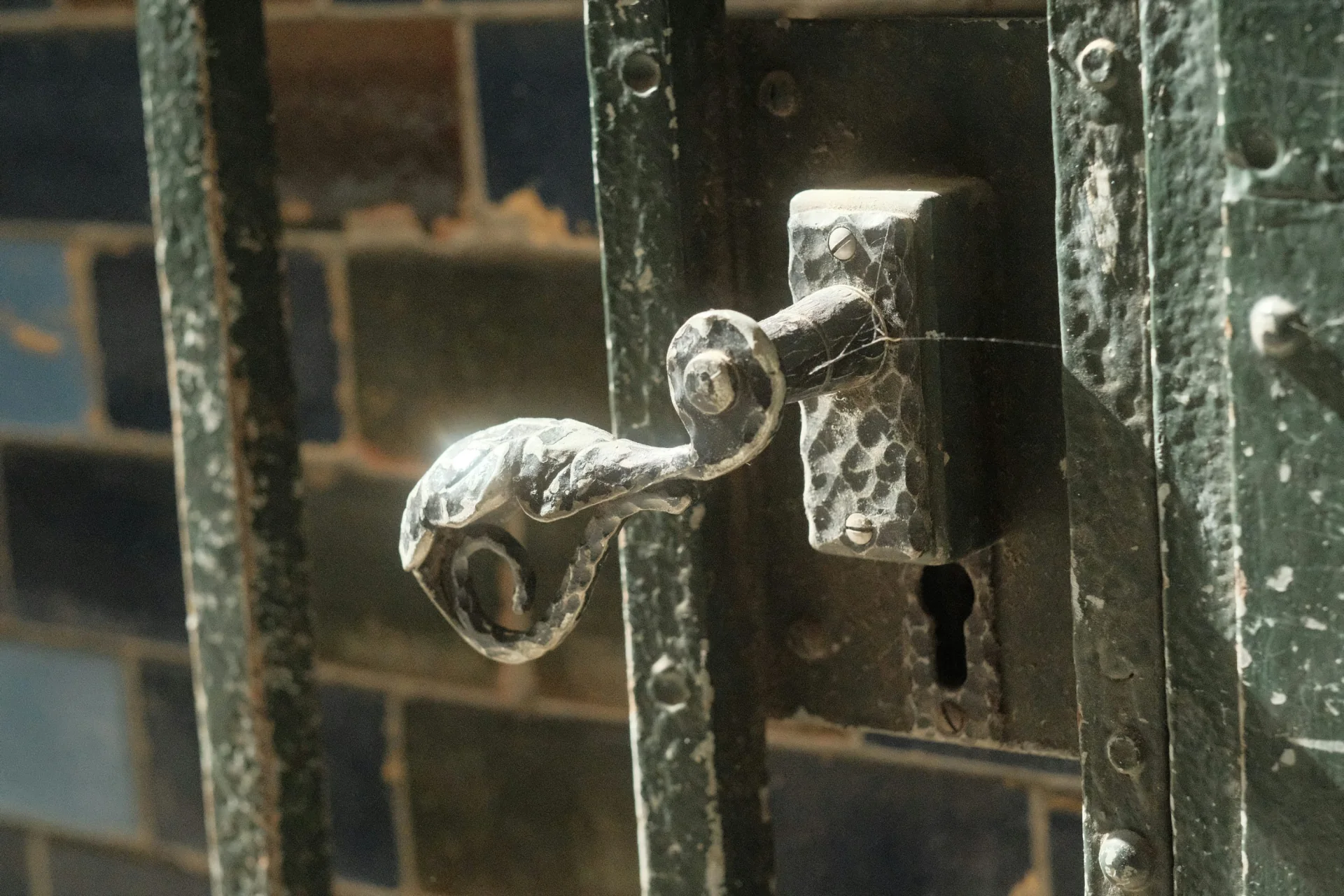 Weathered decorative metal door handle above a keyhole