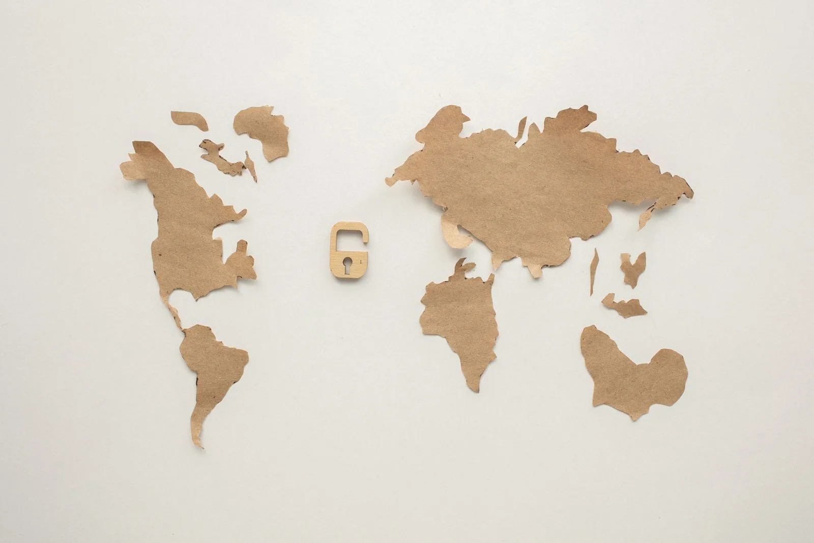 A kraft-paper cut-out of the world map with a small open padlock between the continents.